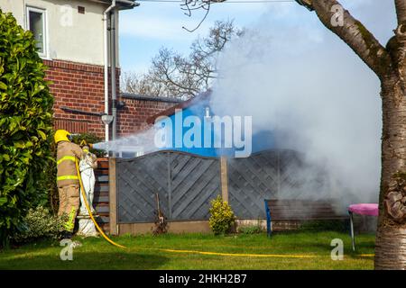 Firemen from the Cheshire fire and recue service attending a garden shed fire Stock Photo