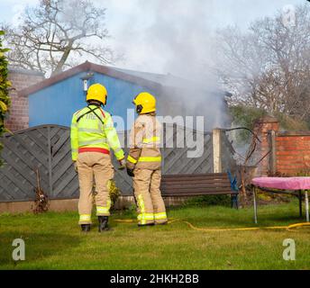 Firemen from the Cheshire fire and recue service attending a garden shed fire Stock Photo