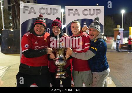 Manchester United fans pose with a replica FA Cup trophy outside the ground before the Emirates FA Cup fourth round match at Old Trafford, Manchester. Picture date: Friday February 4, 2022. Stock Photo