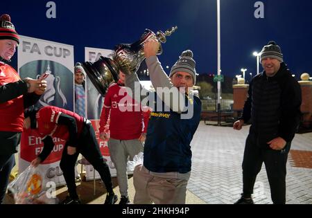 Manchester United fans pose with a replica FA Cup trophy outside the ground before the Emirates FA Cup fourth round match at Old Trafford, Manchester. Picture date: Friday February 4, 2022. Stock Photo