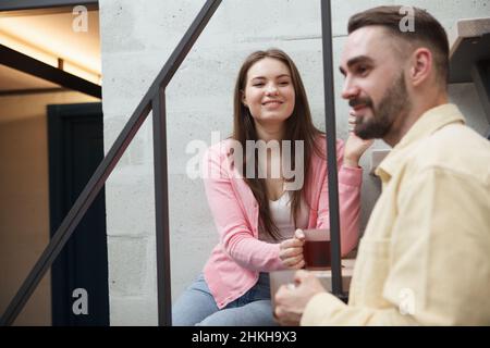 Cheerful beautiful woman smiling at her boyfriend, having tea relaxing at home together Stock Photo