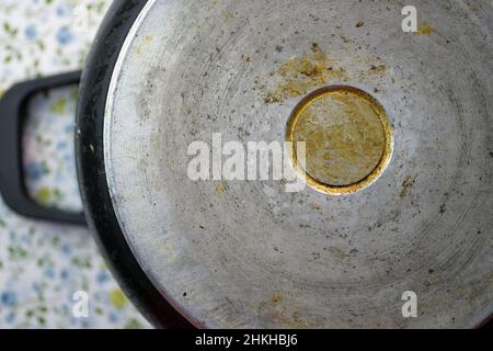The reverse side of the pan is a top view. An old metal pan with drops of fat. The bottom of the cooking pot. Stock Photo