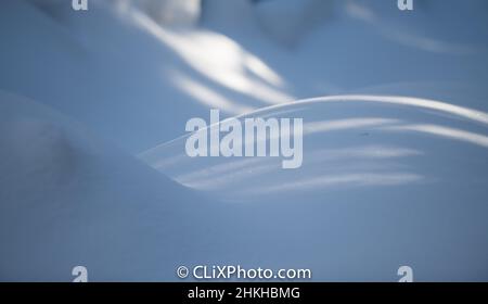 shadows cast on fresh snow on snow mounds or hills of snow curved lines in snow snowscape horizontal format white winter backdrop background type room Stock Photo