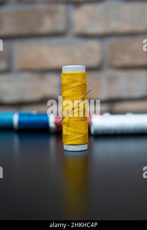 yellow sewing thread on brick and black background for designers Stock Photo