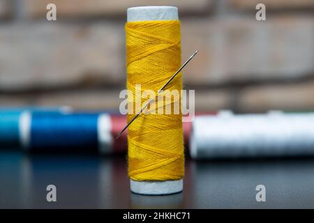 yellow sewing thread on brick and black background for designers Stock Photo
