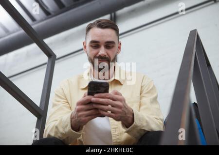 Low angle portrait of a handsome bearded man using smart phone Stock Photo