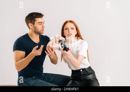 Studio shot of young man trying to draw attention of woman playing video games on white isolated background. Stock Photo