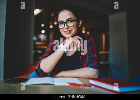 Satisfied female student doing homework in cafe Stock Photo