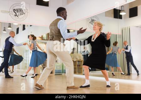 Lady learning to dance lindy hop with man in dance school Stock Photo