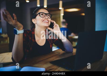 Joyful freelancer talking on phone in cafe Stock Photo
