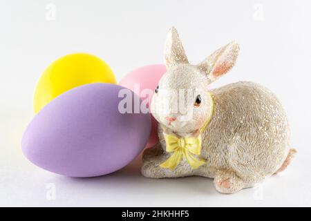 Easter bunny figurine with three Easter eggs on white background.  Close up view. Stock Photo