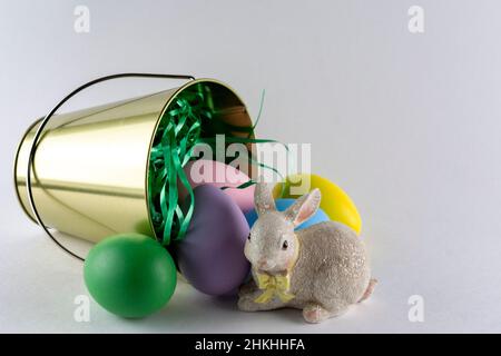 Easter bunny figurine with a pail of Easter eggs on white background with copy space. Stock Photo