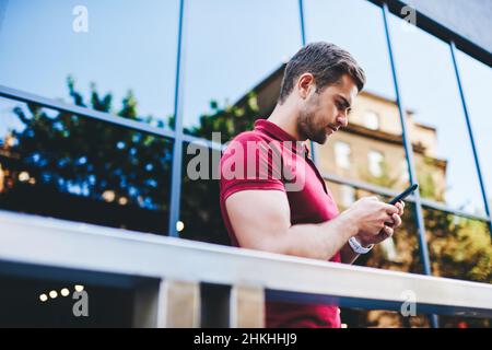 Concentrated young man messaging using mobile phone Stock Photo