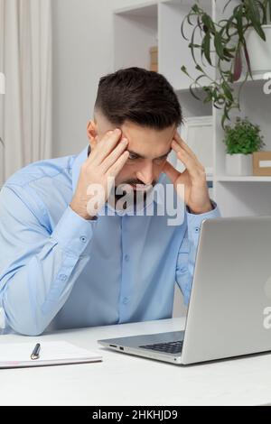 Pain in the head of a tired business man working on a laptop. Stock Photo
