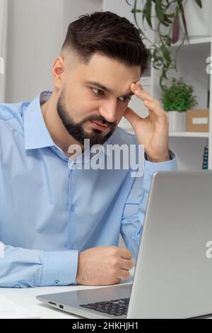 Pain in the head of a tired business man working on a laptop. Stock Photo