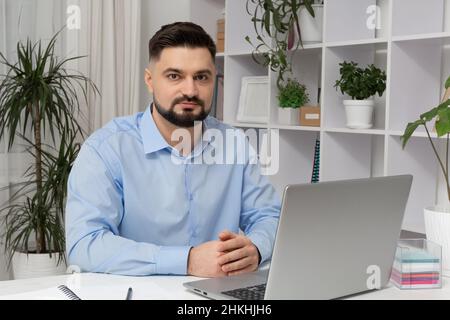 Portrait of a business man sitting at his workplace with a laptop. Stock Photo