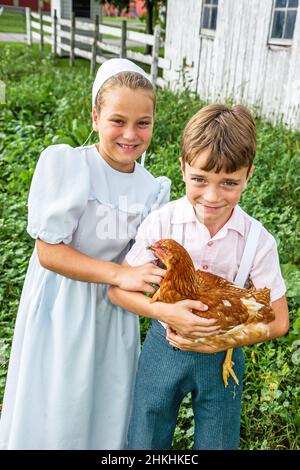 Shipshewana Indiana,Amish Farm Tour,siblings brother sister wearing kapp,boy girl kids children holding chicken Stock Photo