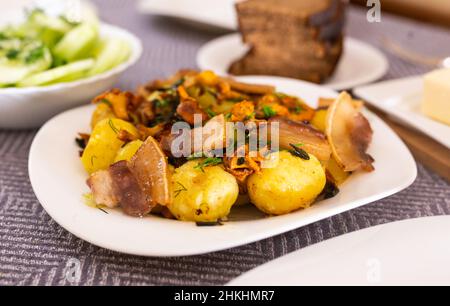 baked potatoes with chanterelles and bacon served with herbs on white plate Stock Photo