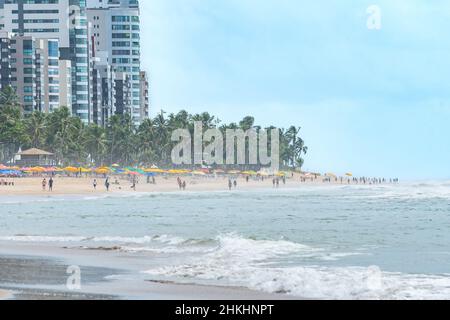 Morning at the beach of Boa Viagem in Recife, Pernambuco state, Brazil. People on the beach, the sand strip, the sea, coconut trees and the city build Stock Photo