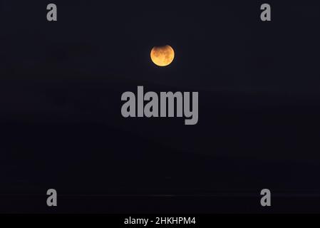 Landscape image of partial lunar eclipse during November 2021 which conincided with blood red moon phoase Stock Photo