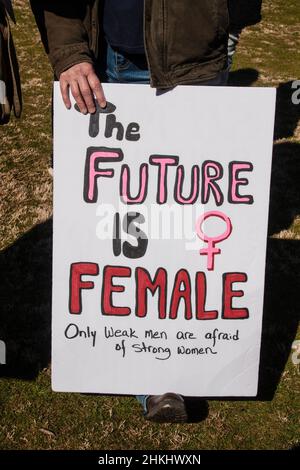 Person in jeans and leather jacket holding protest sign - the future is female Only weak men are afraid of strong women Stock Photo