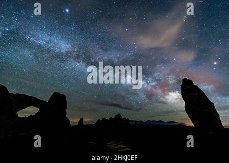 The night sky filled with a few clouds and the Milky Way above the North Window in the Windows sections of Arches National Park, Utah. Stock Photo