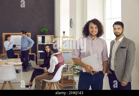Two young office colleagues smiling at the camera, holding documents Stock Photo