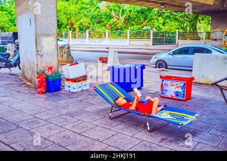 BANGKOK, THAILAND - MAY 12, 2019: The young boy leis and reding book on a camping-cot under the bridge, on May 12 in Bangkok, Thailand Stock Photo