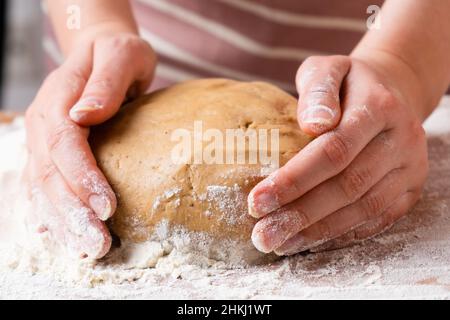 Top view of woman hands kneading the dough for buns, pie, cookies or pastry on the wooden desk. Process of homemade cooking. Stock Photo