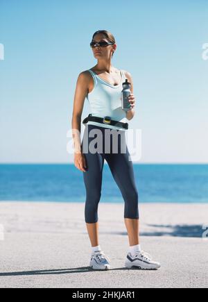 Woman holding a water bottle while standing on a pavement Stock Photo