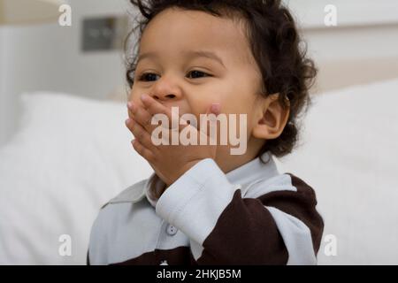 Baby boy holding hand to his mouth Stock Photo
