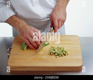 Using kitchen knife to slice avocado into small pieces Stock Photo