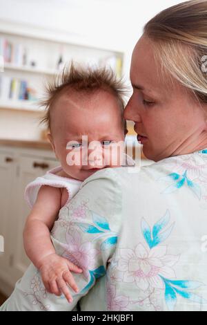 Woman holding a baby girl, looking over the woman's shoulder Stock Photo