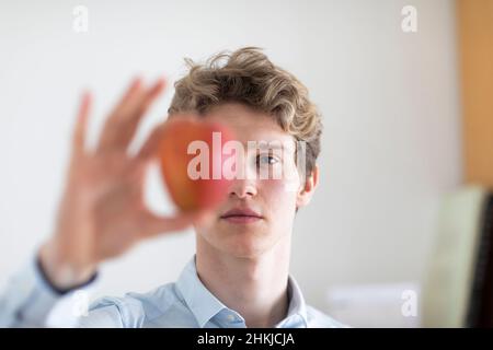 young man with blond hair and an apple in the hand Stock Photo