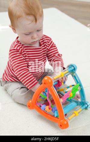 Baby boy playing with abacus style plastic toy Stock Photo