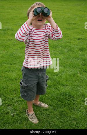 Boy looking through binoculars Stock Photo