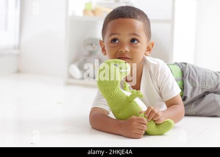 Boy playing with knitted dinosaur toy Stock Photo