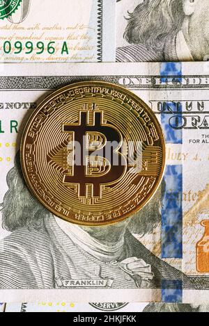 Close up shot of a metal Bitcoin coin on a face of a 100 Dollar banknotes Benjamin Franklin Stock Photo