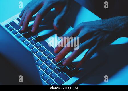 A man Using a laptop computer under blue light. Stock Photo