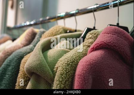 Elegant coats and jackets made of faux fur hang on rack Stock Photo