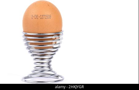 brown chicken egg with imprinted producer code in a silver egg cup, Germany Stock Photo