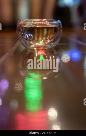 Glassware for hot beverages over blurred background, colorful neon light. Clean teacup.  Stock Photo