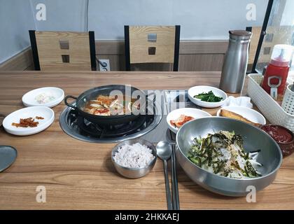 Korean signature Kimchi Stew in a hot ceramic pot served with other side  dishes Stock Photo - Alamy