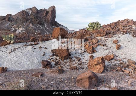 Rust-red boulders tumble down a hill of white ash. Stock Photo