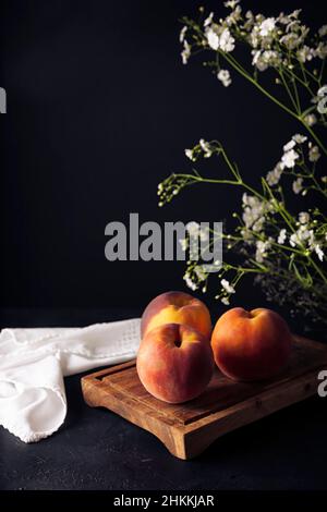 Whole ripe peaches (Prunus persica) on rustic cutting board. Copy space Stock Photo