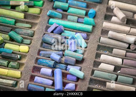 A close up photograph of a box of colorful used chalk pastels