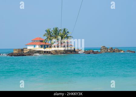 View of the ancient Buddhist temple Seenigama Muhudu Viharaya on the island on a sunny day. Peraliya, Sri Lanka Stock Photo