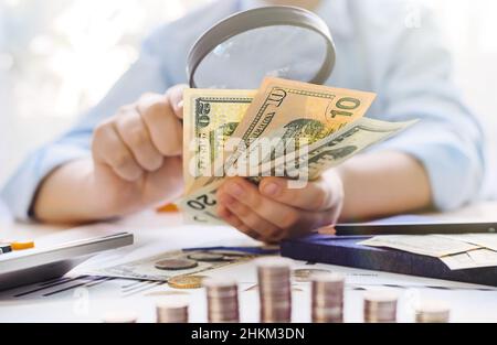 A man examines money through a magnifying glass. Dollars under a magnifying glass. Finance. Income and profit Stock Photo