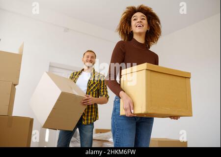 Happy multiethnic couple carrying cardboard box together Stock Photo