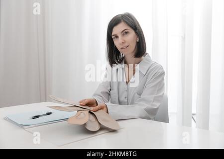 Doctor holding an insole while sitting at a table. Orthopedist tests the medical device. Orthopedic insoles. Foot care. Flat Feet Correction Stock Photo